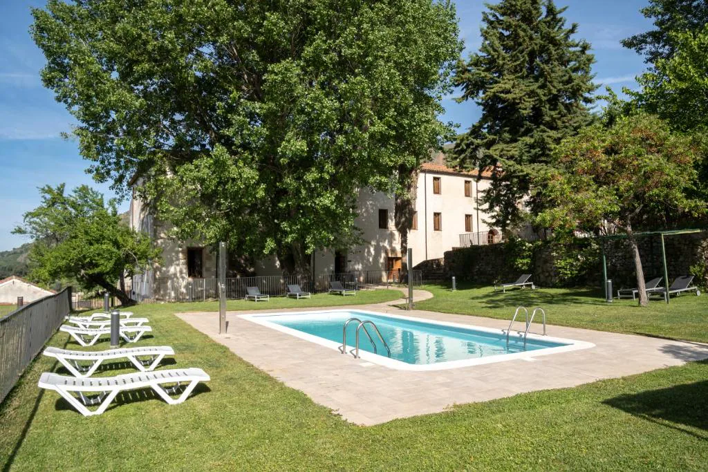 Piscina rectangular en un jardín junto a un antiguo convento