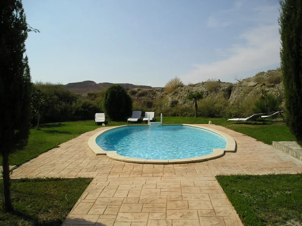 Piscina circular entre jardín y campo