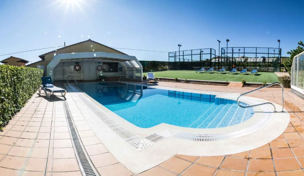 Piscina exterior curva junto a un edificio de piedra