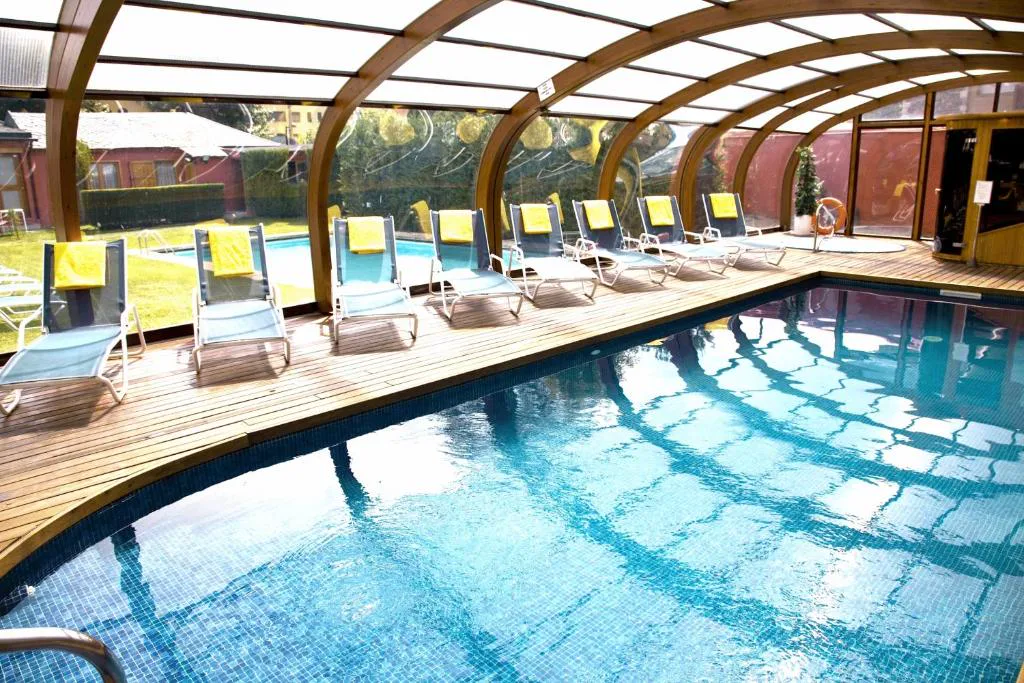 Piscina cubierta con techo de madera y cristal
