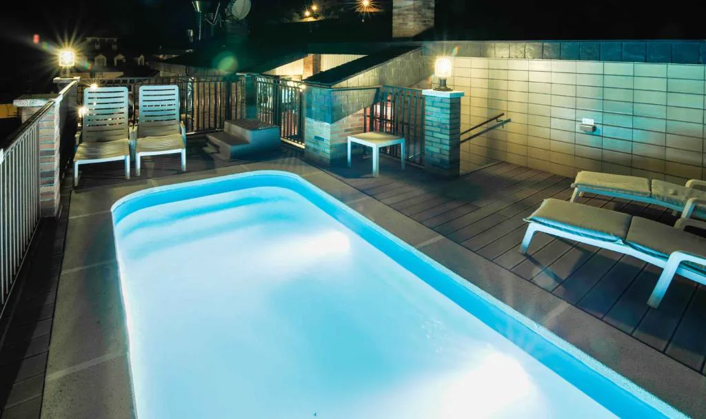Piscina iluminada de noche entre cristaleras