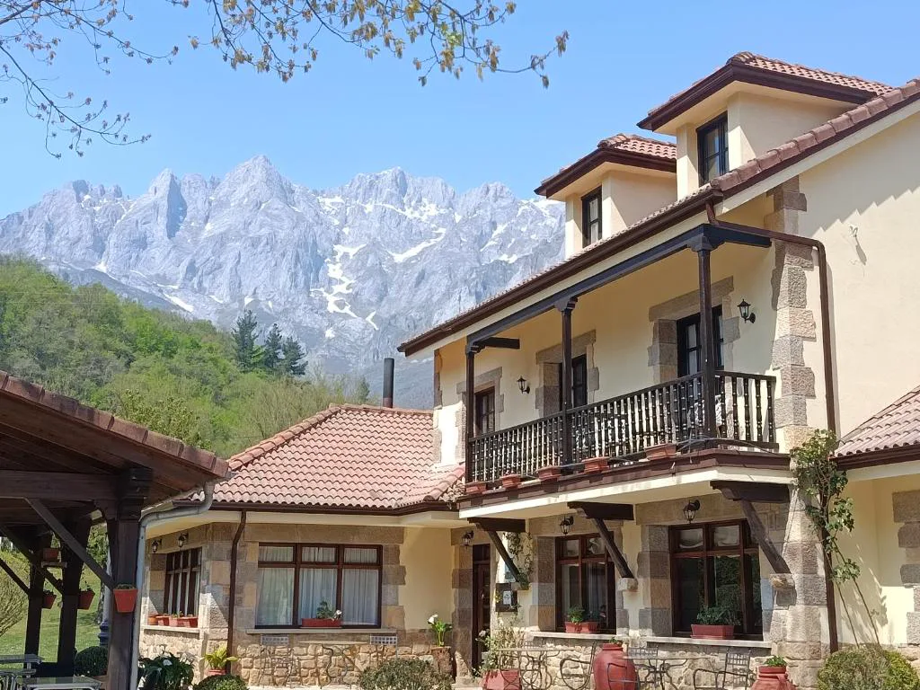 Hotel de dos alturas con balcones y los Picos de Europa detrás