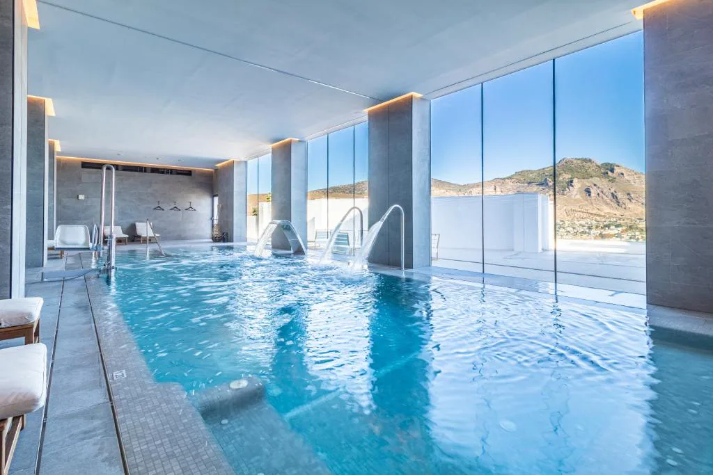 Piscina cubierta con chorros y ventanales junto a la montaña