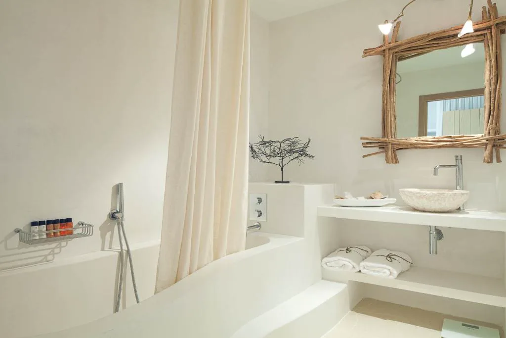 Baño con cortina de lino y espejo de madera flotante, Hotel Es Marès