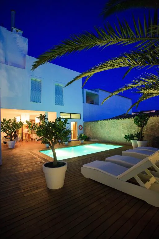 Piscina exterior iluminada al anochecer entre palmeras de Hotel Es Marès, en Sant Francesc Xavier, Formentera
