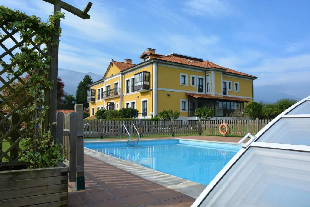 Piscina cubierta parcialmente y hotel amarillo con vistas a la montaña