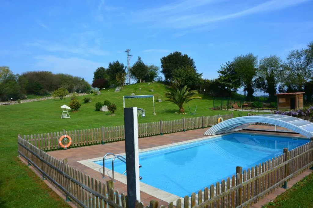 Piscina con valla de madera y prado con porterías