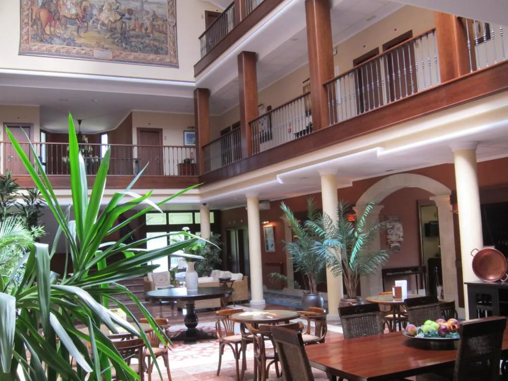 Atrio interior de dos plantas con plantas y mesas