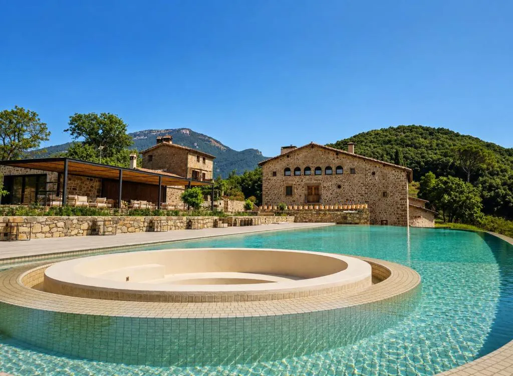 Piscina de borde infinito con la masía de piedra al fondo