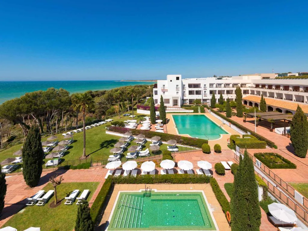 Vista aérea del resort con piscina, jardines y el mar al fondo