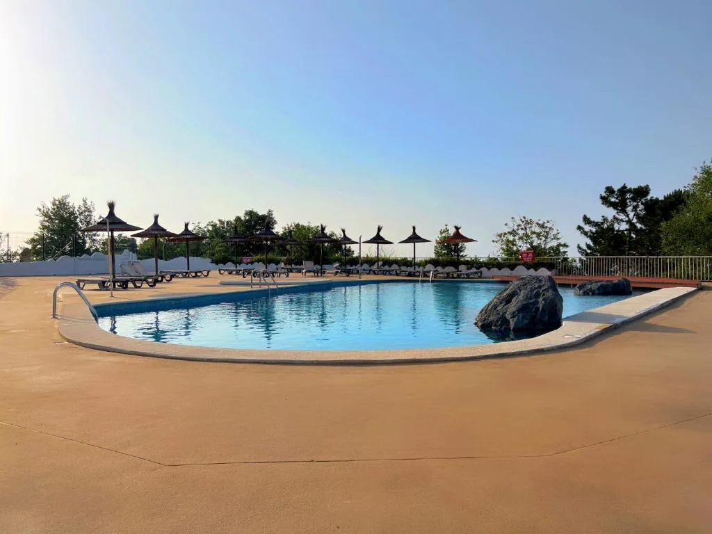 Piscina grande con rocas decorativas y sombrillas