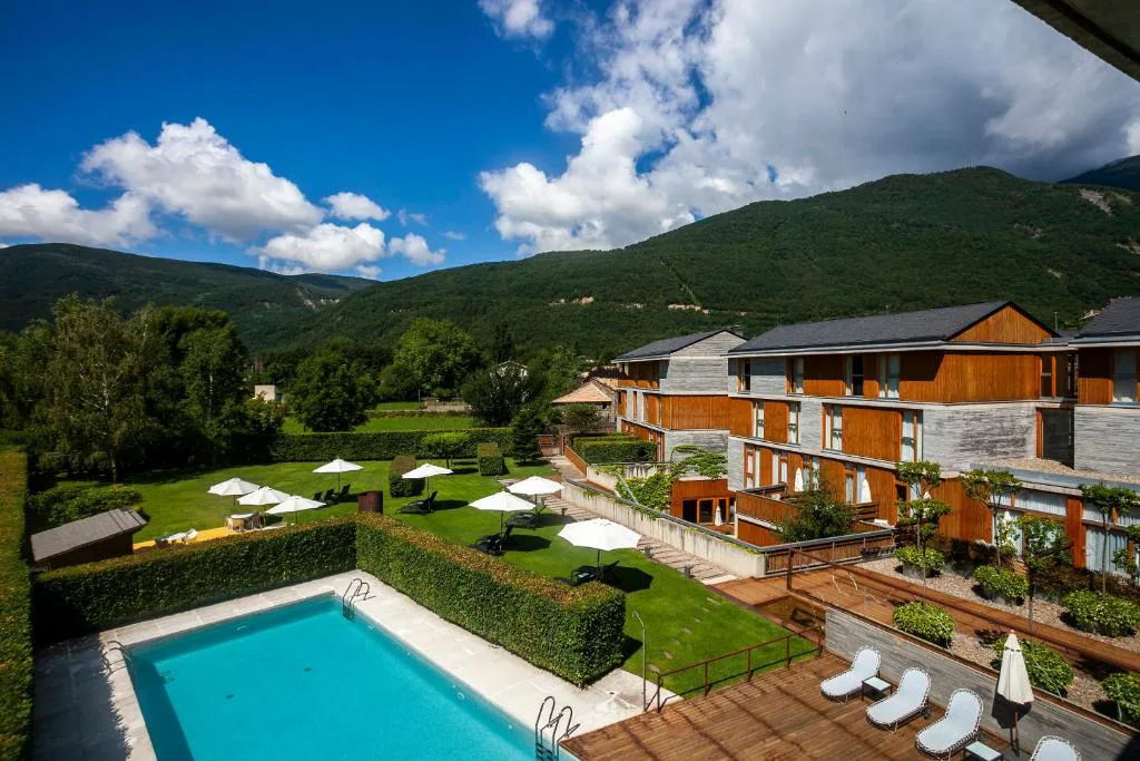 Piscina exterior con tumbonas y jardines frente a las montañas