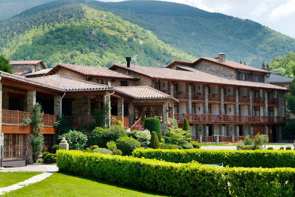 Hotel de piedra y madera con jardín y montañas
