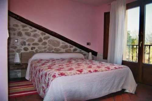 Habitación con paredes de piedra y cama con colcha de flores