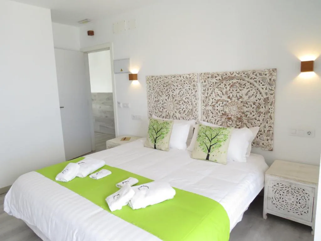 Dormitorio con cabecero de madera tallada y ropa de cama verde, Hotel Lua Boutique