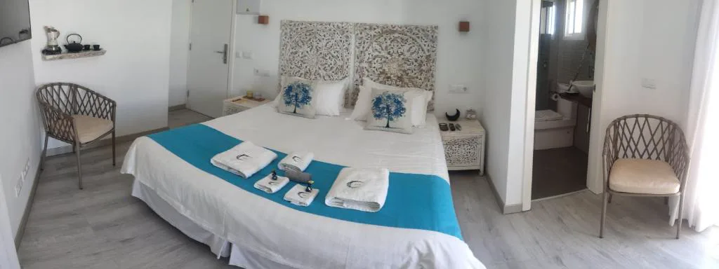 Dormitorio panorámico con sillón de mimbre y vistas al mar a través de una puerta acristalada, Hotel Lua Boutique