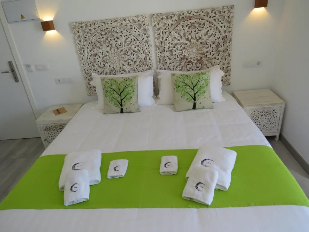 Dormitorio con cabecero tallado y ropa de cama verde con motivo de árbol, Hotel Lua Boutique