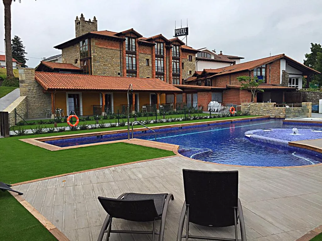 Piscina con zona de chorros y tumbonas frente al hotel