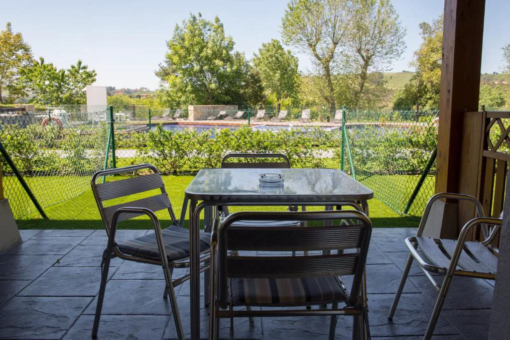 Terraza acristalada con mesa y sillas frente al jardín
