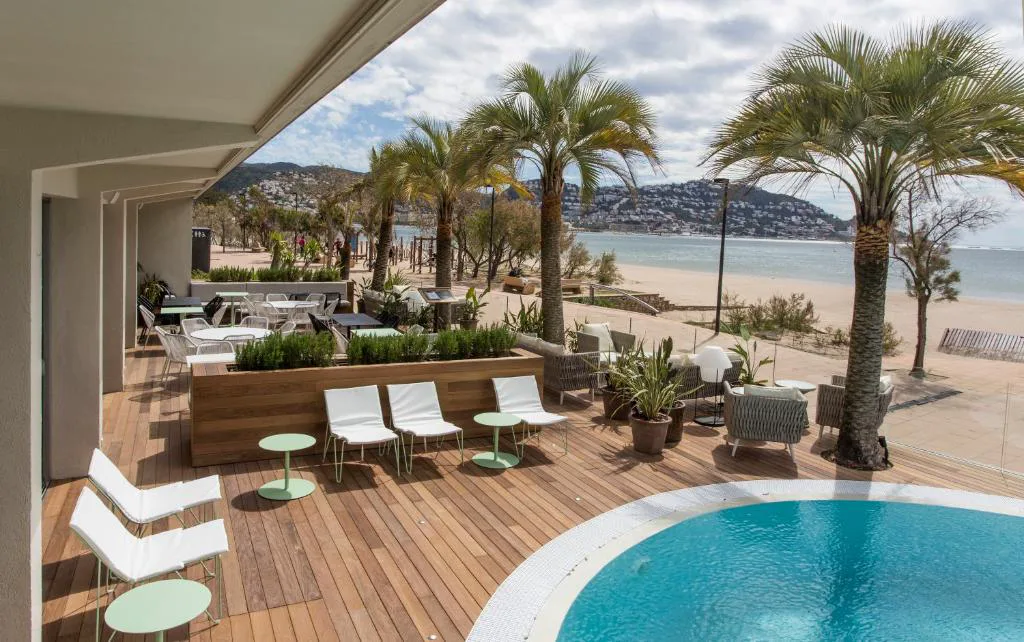 Terraza con piscina y palmeras frente a la playa