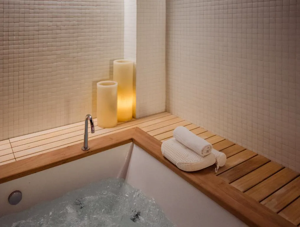 Baño con bañera de madera con banco y velas