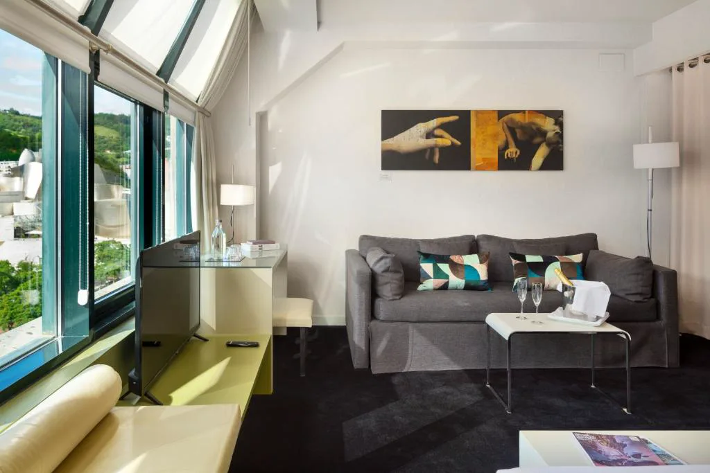 Suite con sofá gris y ventanas inclinadas