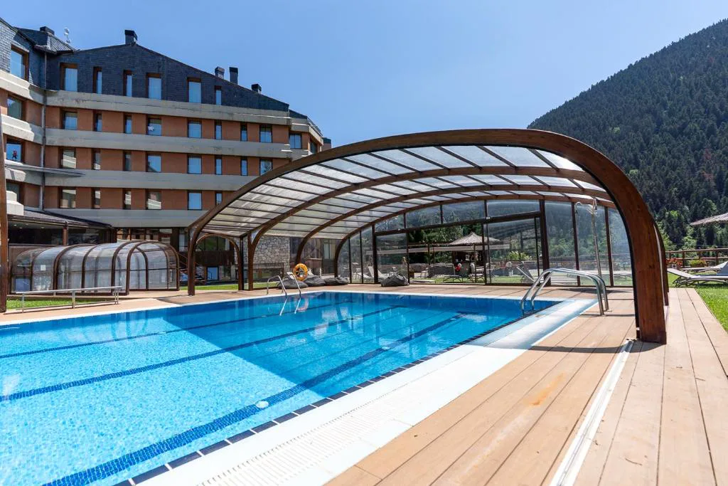 Piscina exterior bajo cubierta retráctil junto a las montañas