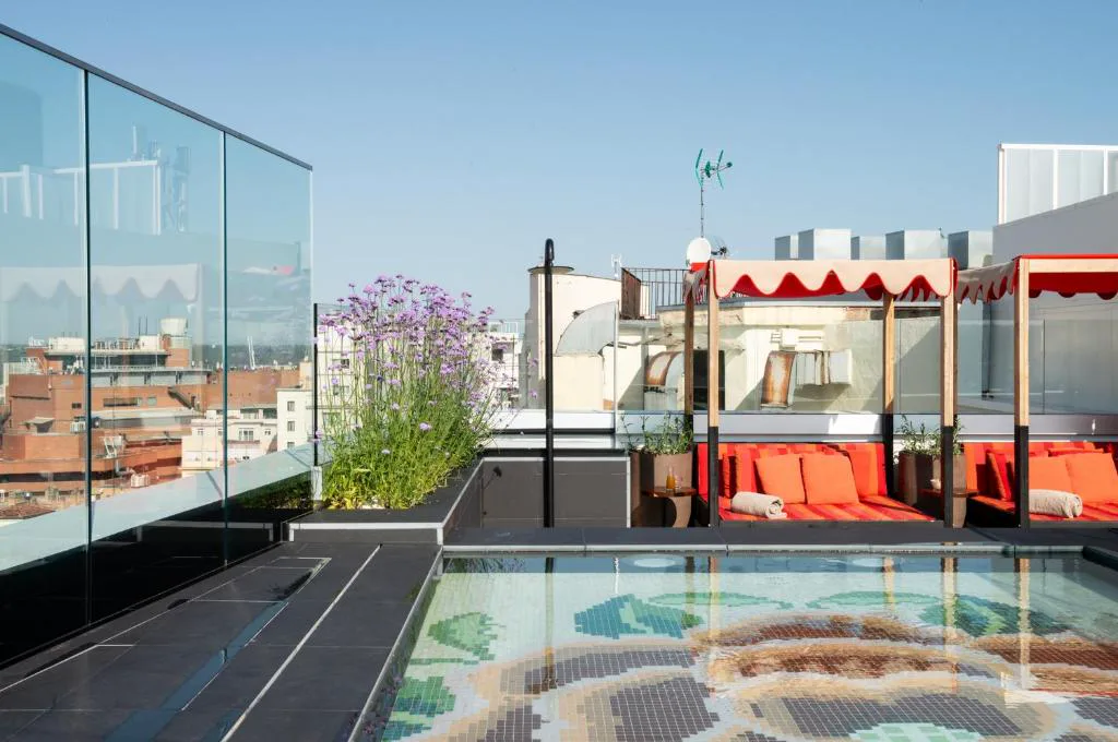 Terraza con piscina de mosaico de flores y tumbonas