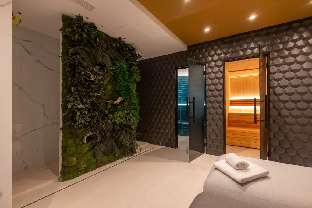 Sauna con puerta de cristal junto a una pared vegetal