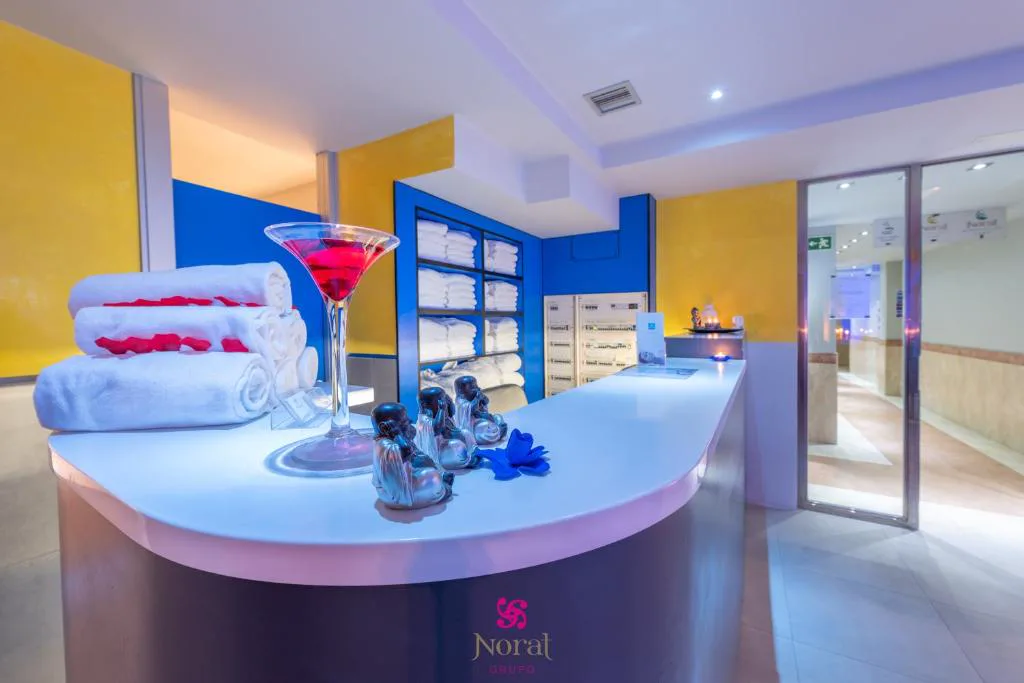 Recepción del spa con toallas enrolladas y copa de cóctel sobre el mostrador, Hotel Norat Marina & Spa