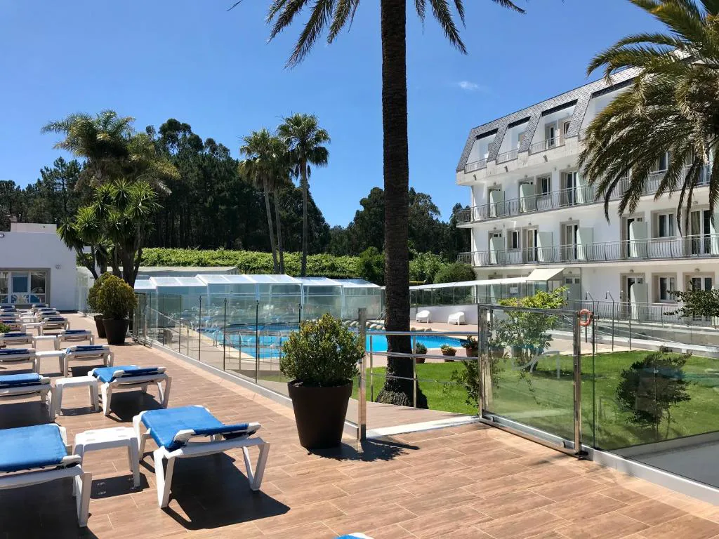 Vista de las dos piscinas, exterior y cubierta, con la fachada del hotel al fondo, Hotel Nuevo Vichona