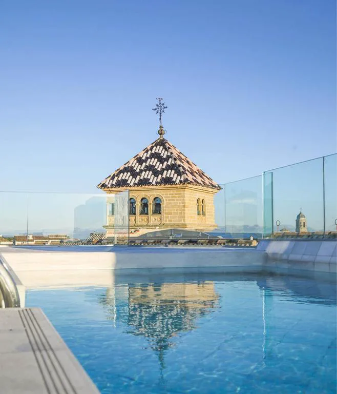 Piscina en la azotea junto a una torre con cúpula de teja
