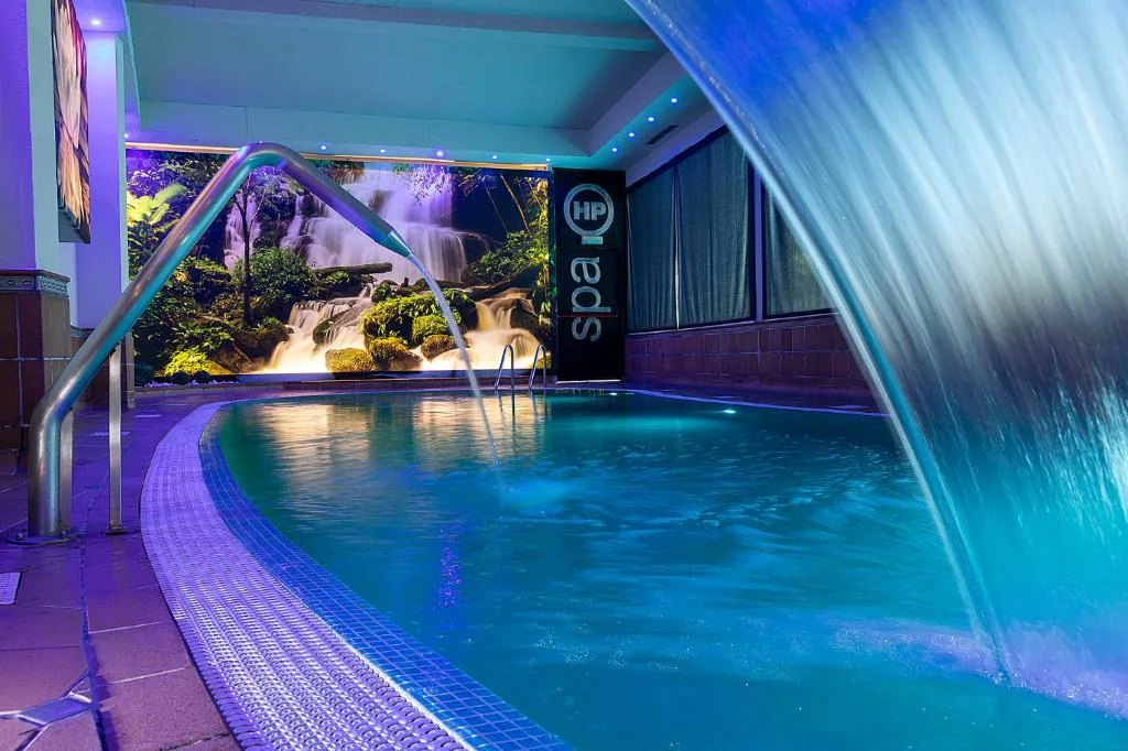 Spa con cascada de agua sobre una piscina iluminada