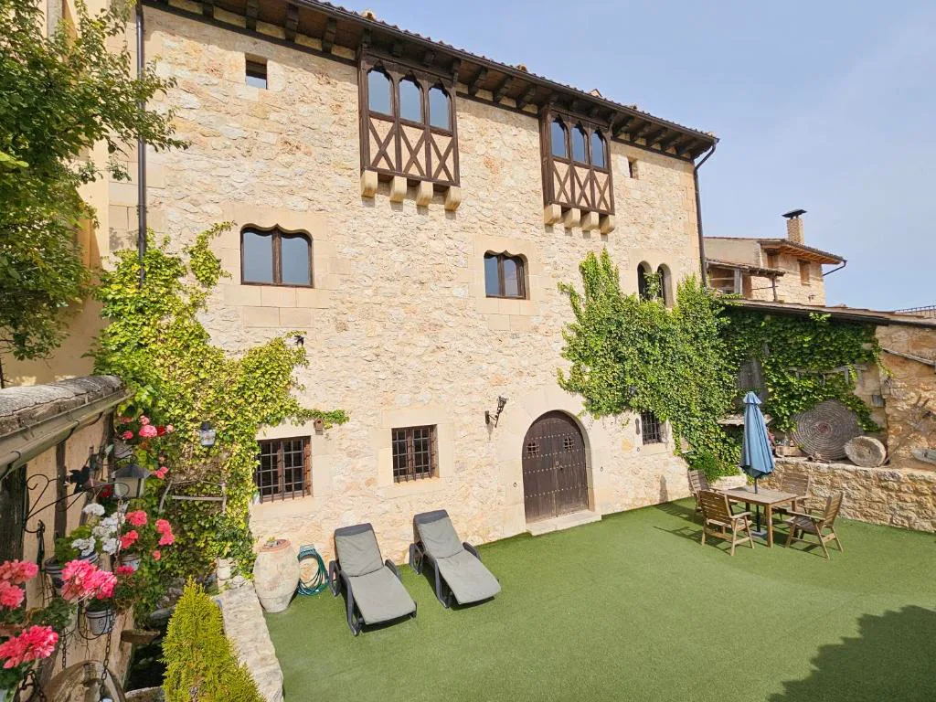 Casa de piedra con jardín de césped, tumbonas y enredaderas