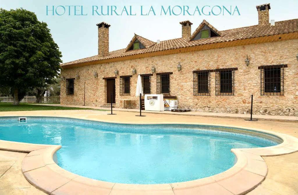 Piscina y edificio de piedra con el rótulo del hotel