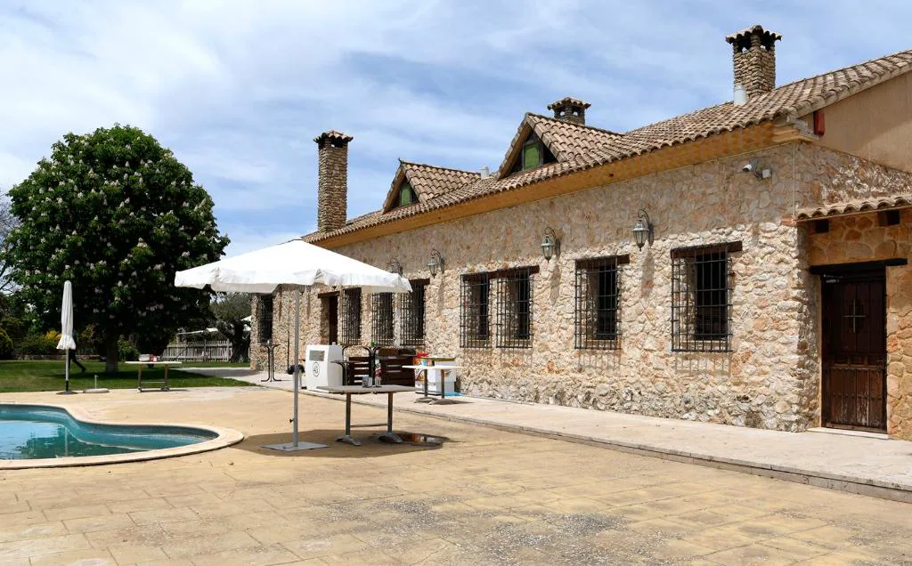 Terraza junto a la piscina y el edificio de piedra