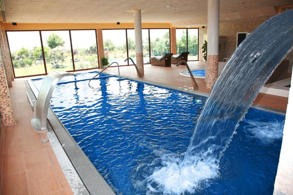 Piscina cubierta con chorro de agua y ventanales al campo