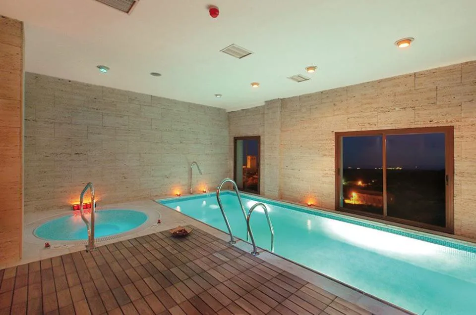 Piscina de spa interior con paredes de piedra y luz cálida