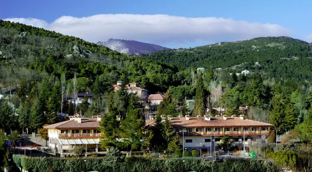 Hotel de piedra y madera rodeado de pinos bajo las montañas