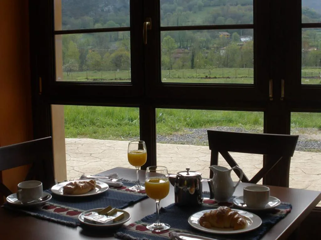 Desayuno con zumo y bollería junto a una ventana con vistas al prado