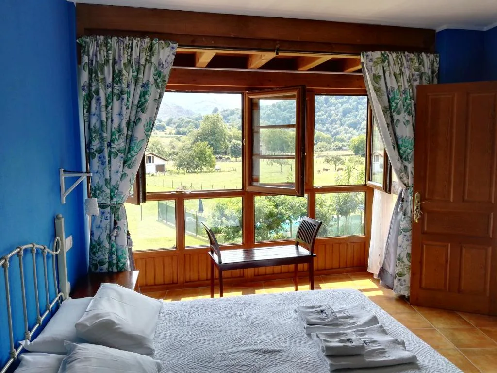 Habitación con ventanal, cortinas floreadas y pared azul