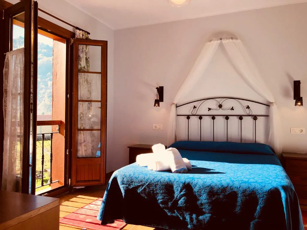 Habitación con cama de forja, dosel blanco y balcón