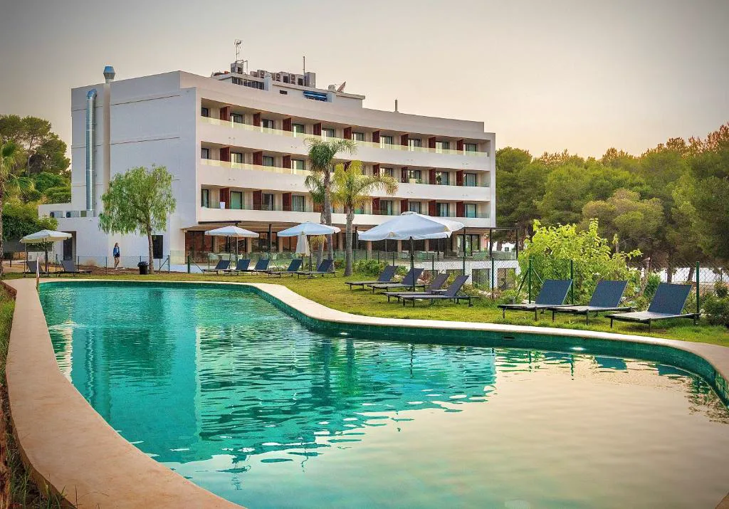 Piscina exterior al atardecer frente al edificio del hotel