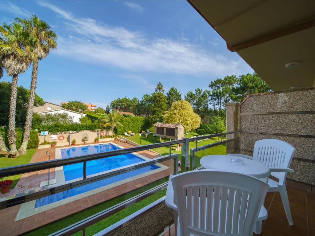 Balcón con vistas a la piscina exterior y jardín con palmeras, Hotel Spa Atlántico