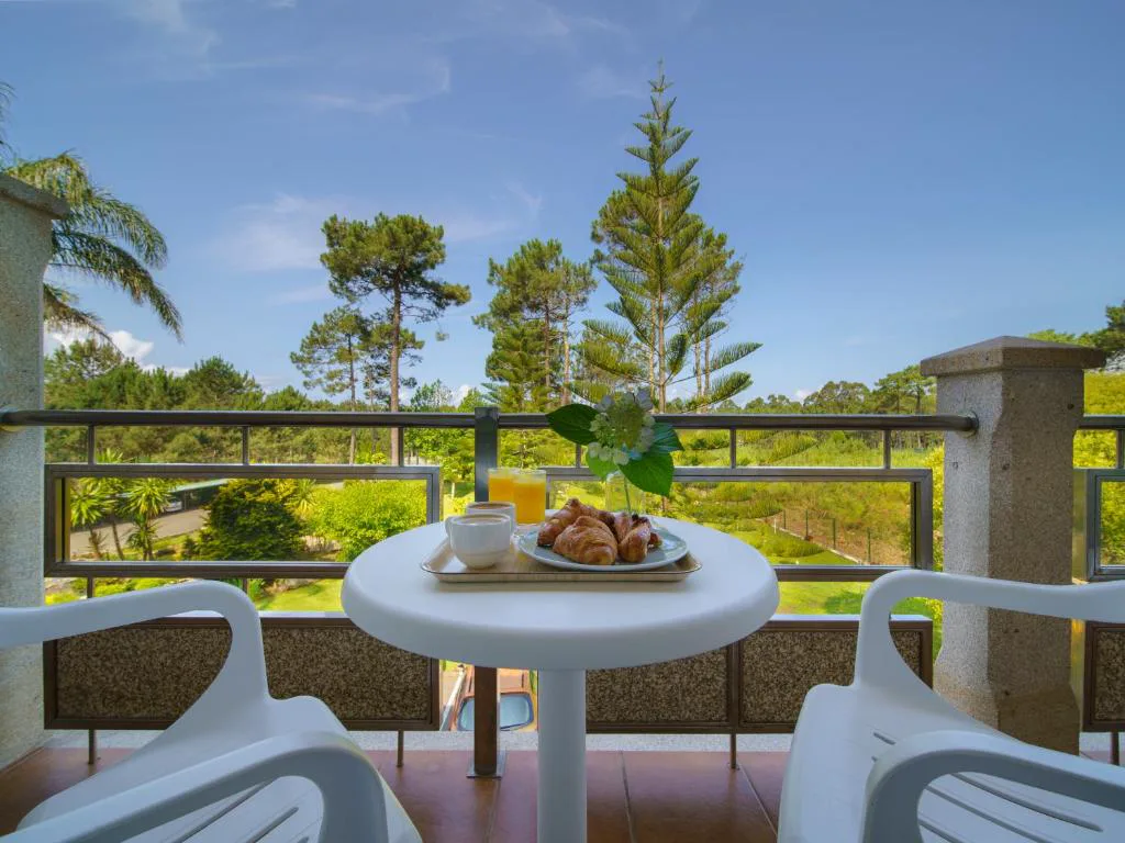 Desayuno con zumo de naranja y cruasanes en el balcón entre pinos, Hotel Spa Atlántico