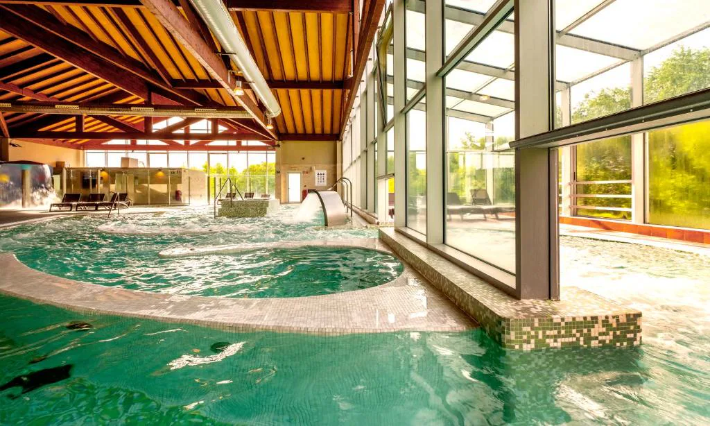 Piscina termal activa bajo pabellón de madera con chorros y jacuzzi circular, Hotel Spa Attica21 Vilalba