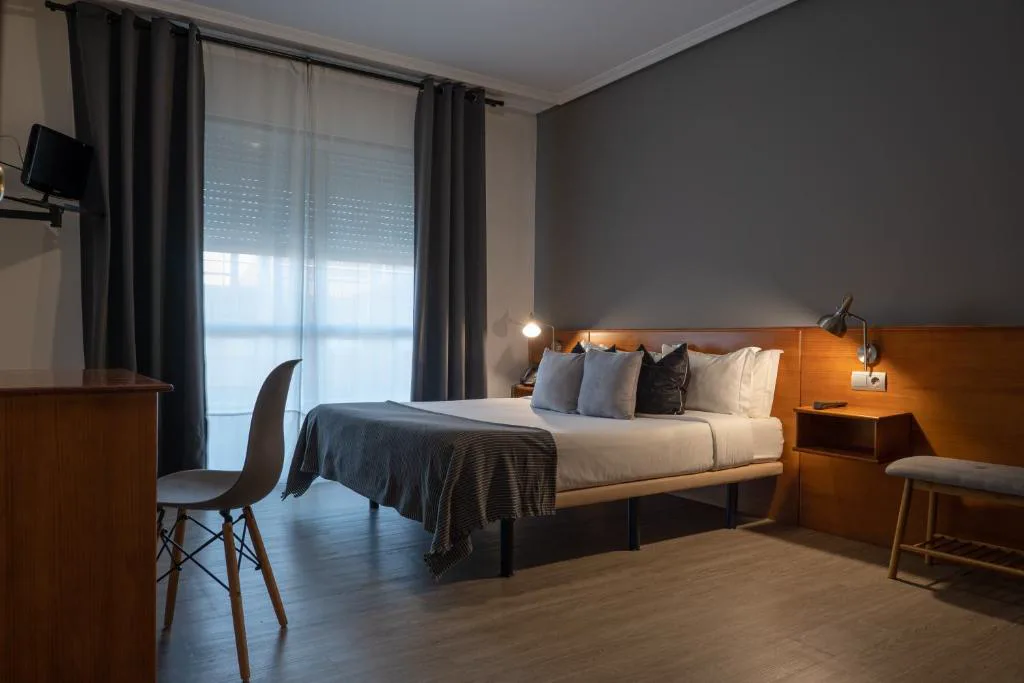 Habitación doble en tonos grises con cabecero de madera, Hotel & Spa Carlos desde 1996