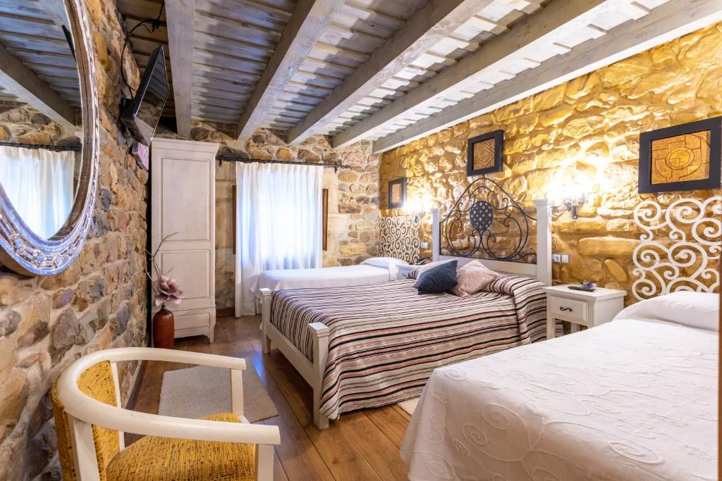 Habitación de piedra y vigas con camas y sillón