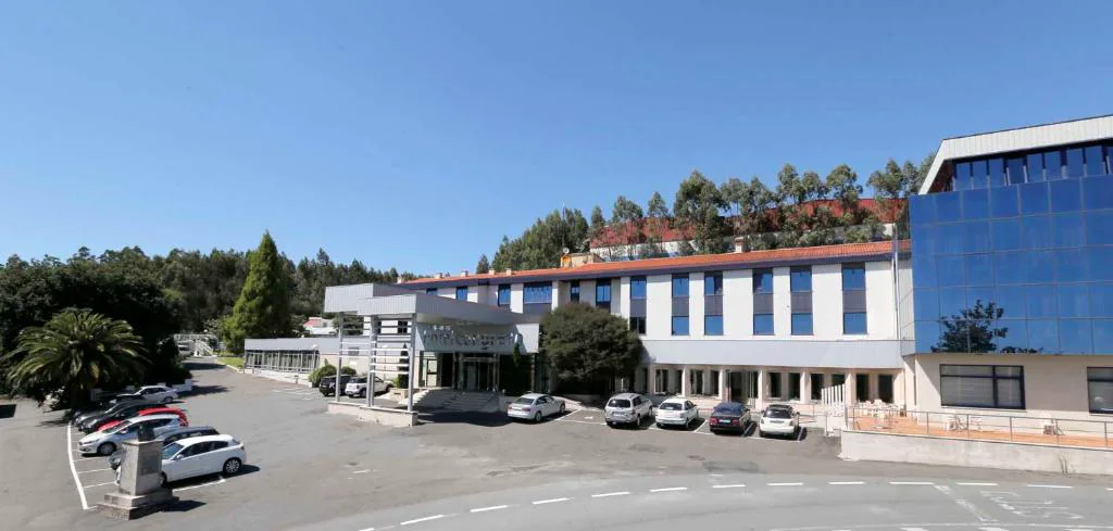 Fachada del hotel con aparcamiento y fachada acristalada moderna, Hotel Spa Congreso