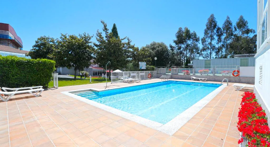 Piscina exterior en jardín con césped y arbolado, Hotel Spa Congreso